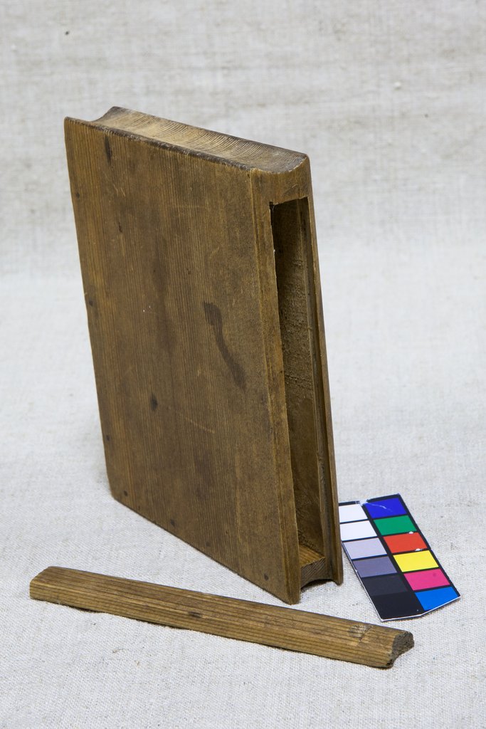 Деревянный прямоугольный ящик для хранения книги с выемкой сбоку, рядом лежит узкая деревянная планка - крышка для боковой прорези