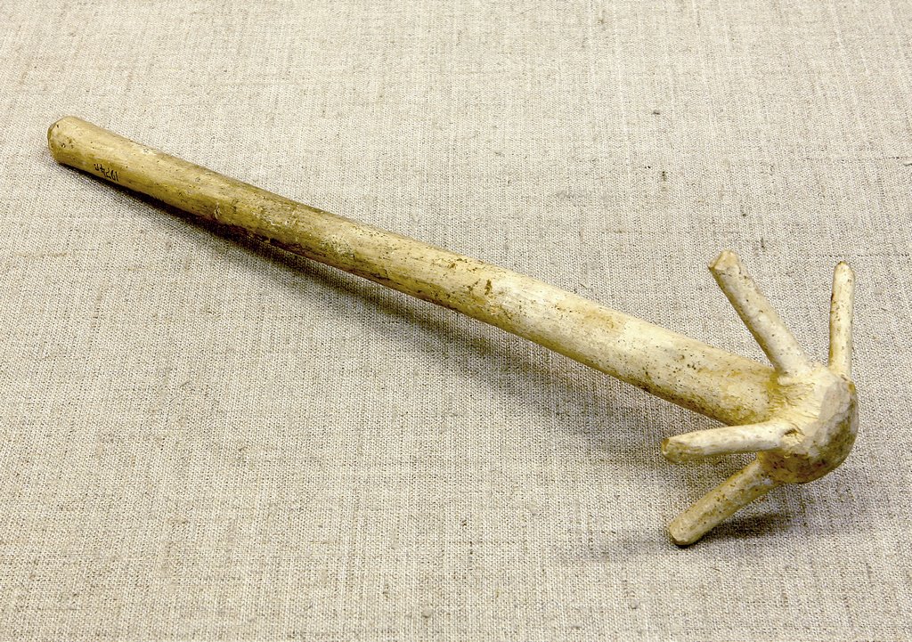 Старинная деревянная мутовка естественной фактуры и цвета с длинной рукоятью и пятью короткими, поднятыми к верху концами. Ручка имеет следы загрязнений от частого использования. Использовалась для размешивания жидкого теста.