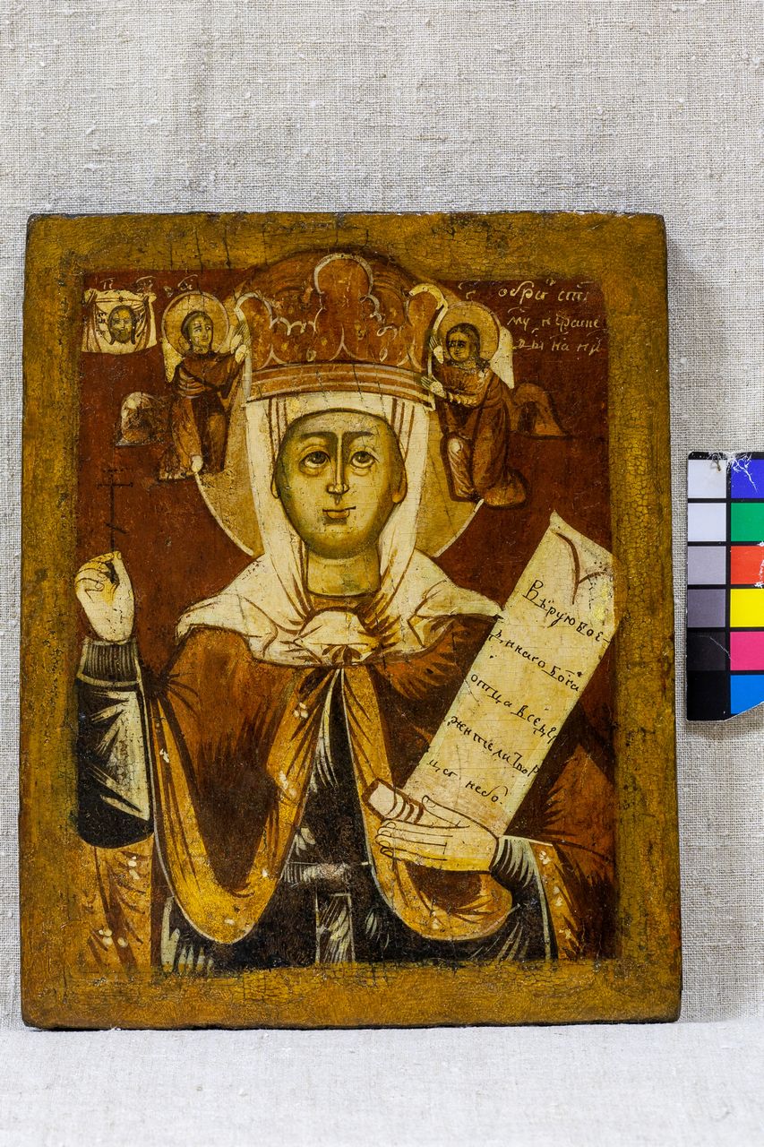На иконе изображена женщина в богатых одеждах и короне, она держит свиток с текстом. За её плечами, по бокам, расположены два ангела с нимбами на тëмно-коричневом золотистом фоне