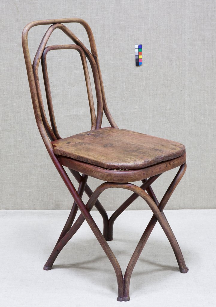 Деревянный стул без подлокотников с изогнутыми дугами основания и спинки. Плоское, слегка изношенное квадратное сиденье с округлыми углами. Ножки в форме перекрещивающихся дуг придают лёгкость. Высокая спинка из вложенных рамок-дуг разного размера.