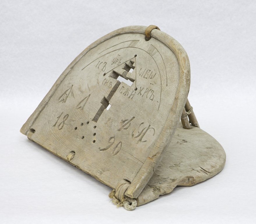Старинный поплавок, изготовленный из дерева и имеющий арочную форму, украшен вырезанным насквозь крестом и надписями на древнеславянском языке. Нижняя надпись дата создания предмета 1890 год. Поверхность изношена, видны следы хранения и времени.