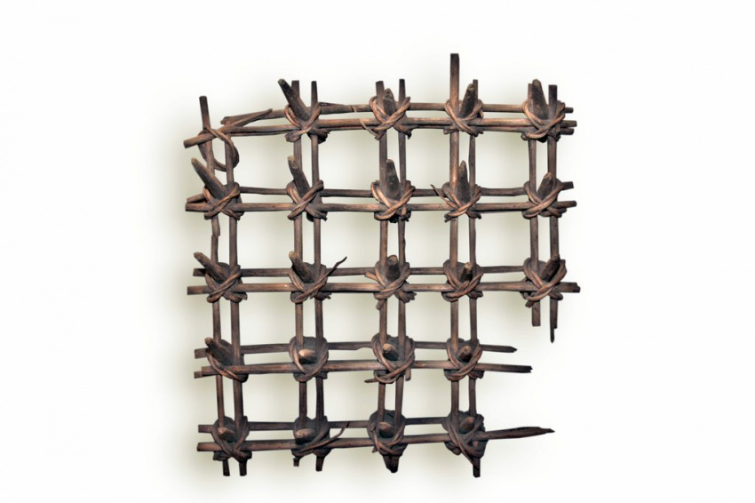 Квадратная решётка из деревянных палочек, попарно связанных между собой.  В местах пересечения они стянуты толстыми узлами из веток, между пересечениями образуются равные по размеру клетки, по углам которых закреплены деревянные зубцы для рыхления грунта.