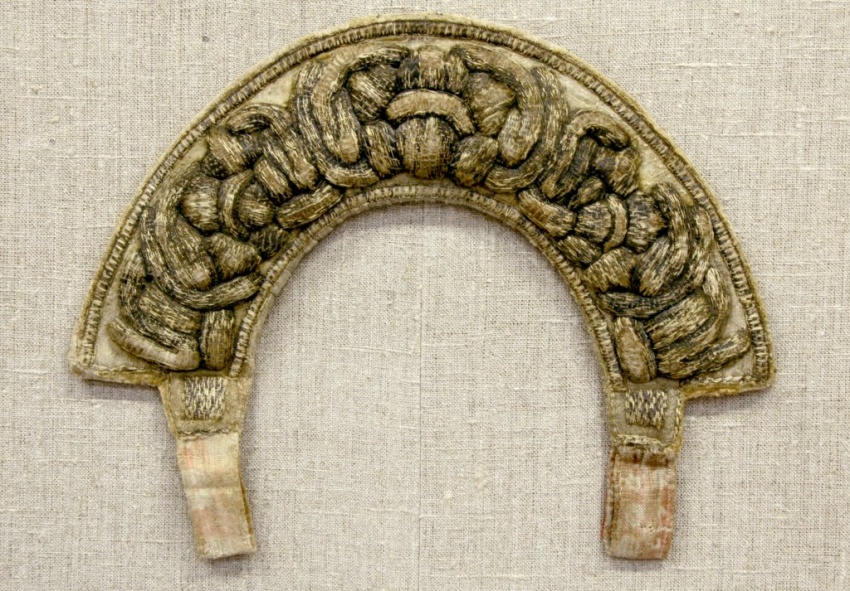 Головной убор, по форме напоминающий перевëрнутую подкову.  Золотисто-бежевый фон покрывает выпуклая плотная вышивка в виде  узловатых, сплетенных между собой элементов, выполненных золотыми нитями