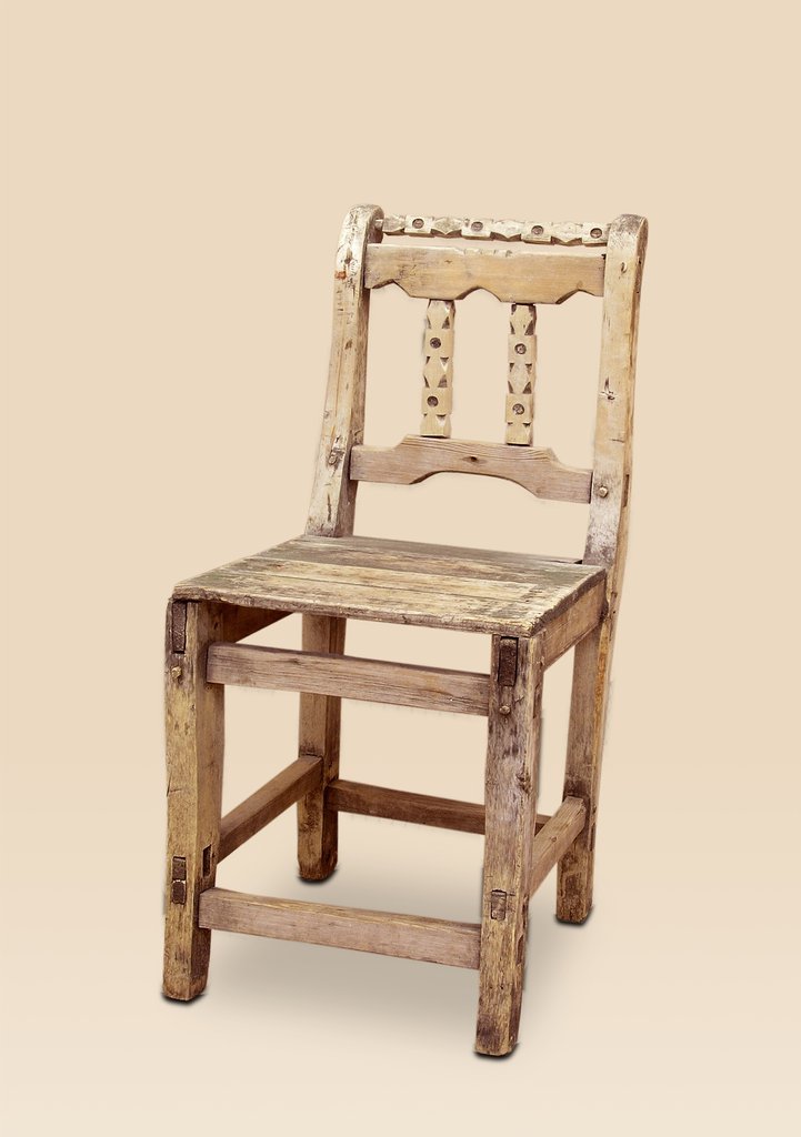 Деревянный стул со спинкой из двух вертикальных перекладин и тонких досок с отверстиями. Плоское сиденье из дощечек. Потёртости и облезшая краска создают изношенный, но крепкий вид. Цвет светлый с тёмными пятнами.