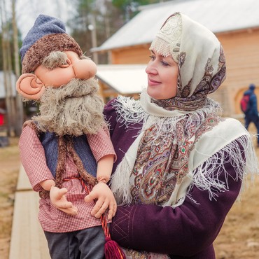 На фотографии девушка в народном костюме улыбается кукле сказочного персонажа - Сене Малине, которого она держит на руках