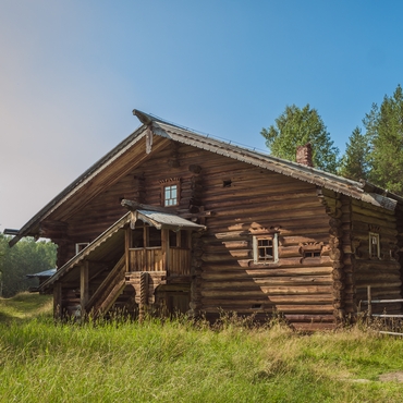 На фотографии изображён деревянный дом с высоким крыльцом